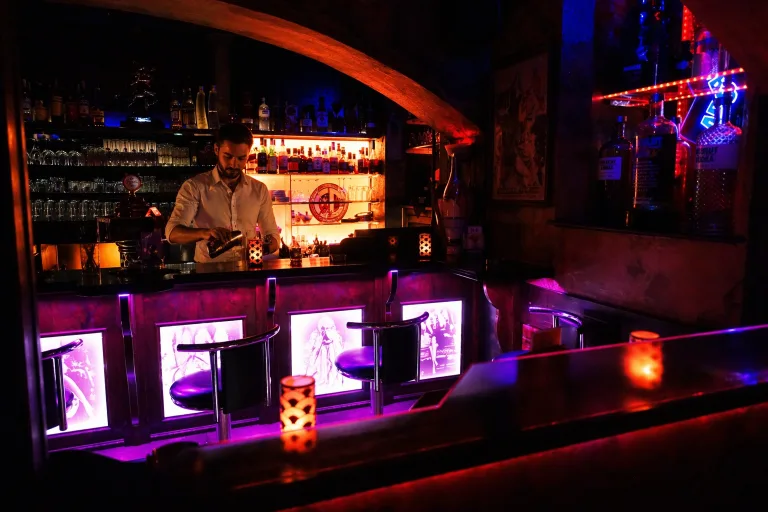 Barmann hinter stimmungsvoller Bar im Neonlicht
